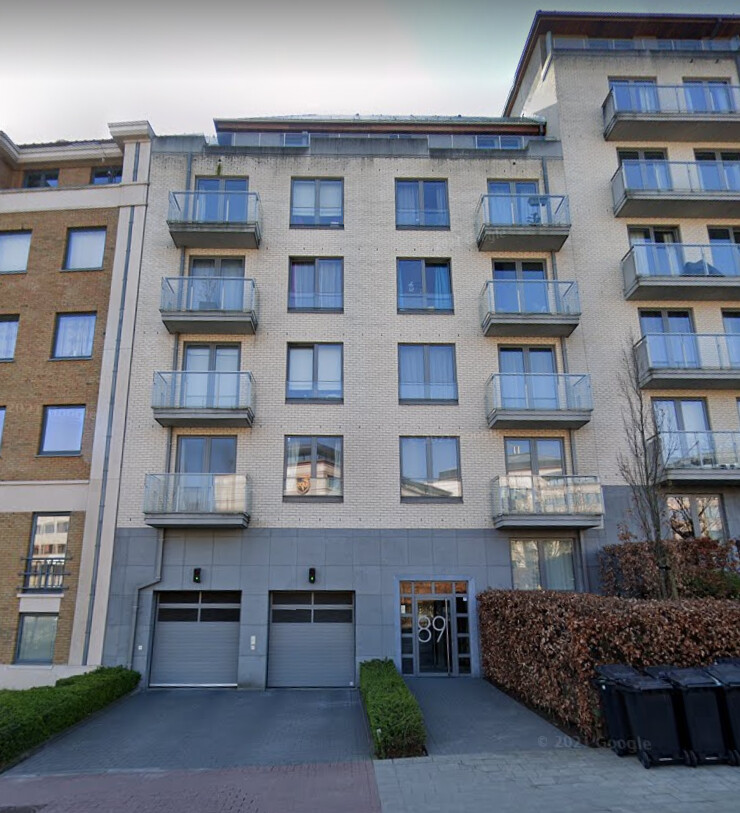Immeuble résidentiel moderne avec façade en briques claires, balcons vitrés et double garage, situé au numéro 89.