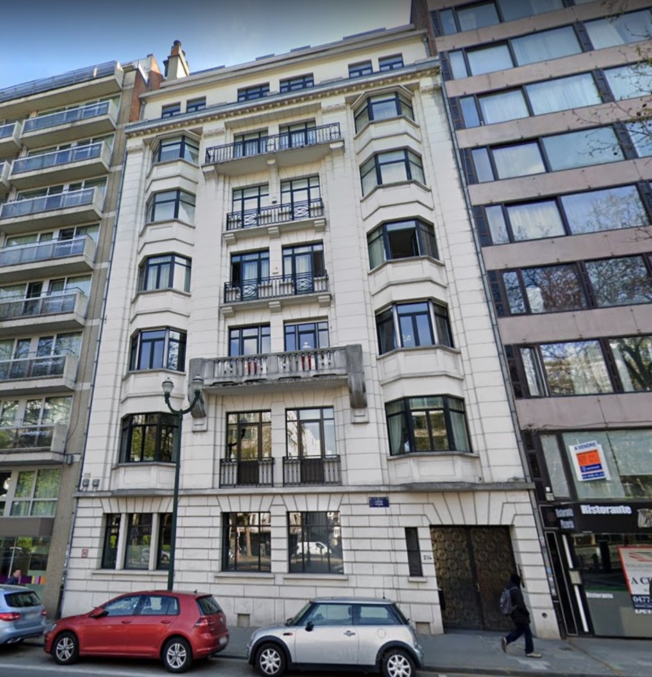 Immeuble blanc de style classique avec balcons en fer forgé et grandes fenêtres, situé entre deux bâtiments modernes, rue Churchill.