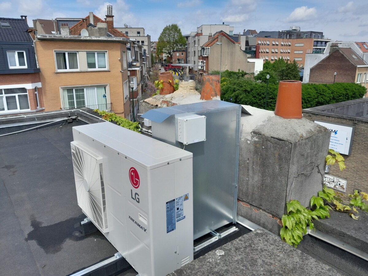 Unité extérieure de climatisation LG installée sur un toit plat, entourée de bâtiments en briques et de végétation urbaine.