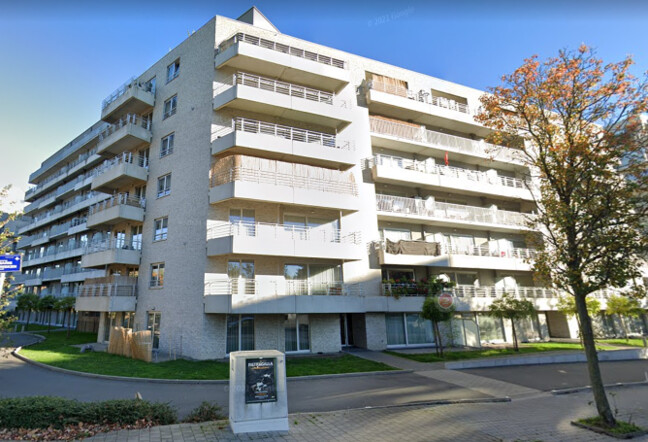Immeuble résidentiel moderne en briques blanches avec balcons, situé à l'angle d'une rue bordée d'arbres, intitulé "West Point".