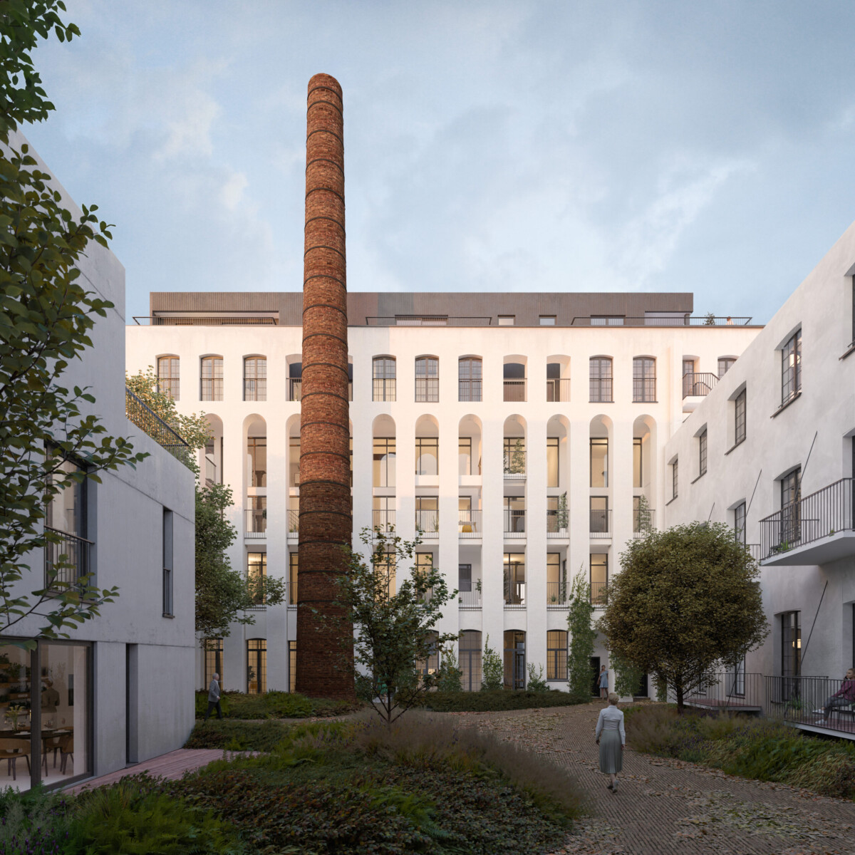 Bâtiment blanc avec une haute cheminée en briques au centre, entouré de végétation et d'un chemin pavé.